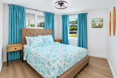 Queen bed, coastal bedding, matching nightstands on both sides — a balanced setup for the adult kids, the in-laws, or whichever couple ends up in here.