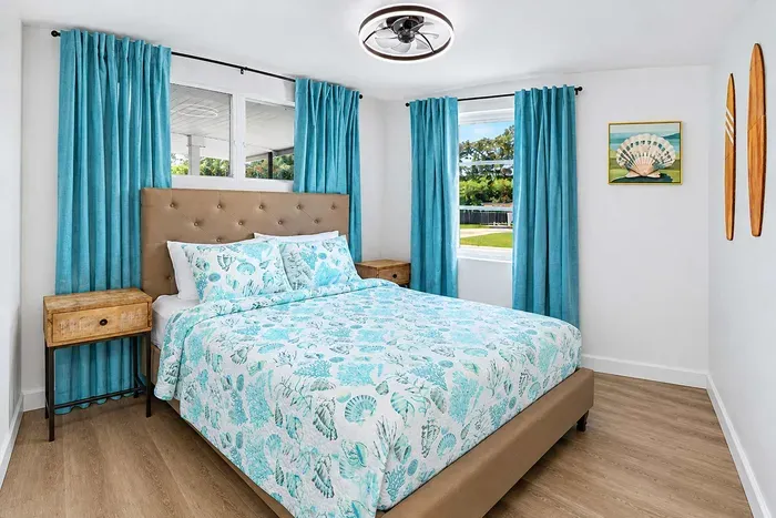 Queen bed, coastal bedding, matching nightstands on both sides — a balanced setup for the adult kids, the in-laws, or whichever couple ends up in here.