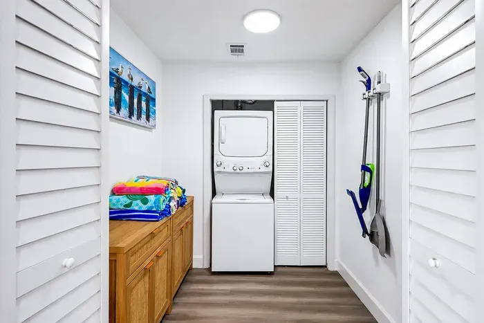 Real washer/dryer, beach towels ready to grab, vacuum on the wall — the honest amenity photo that makes the family-planner exhale.