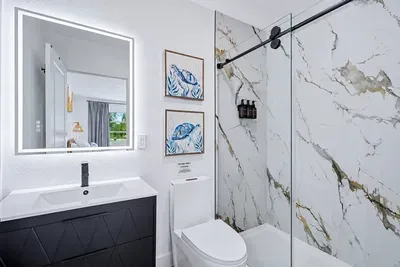 Marble shower walls, glass slider, LED mirror, toiletries ready — the parents' reset button after a full day with the kids.