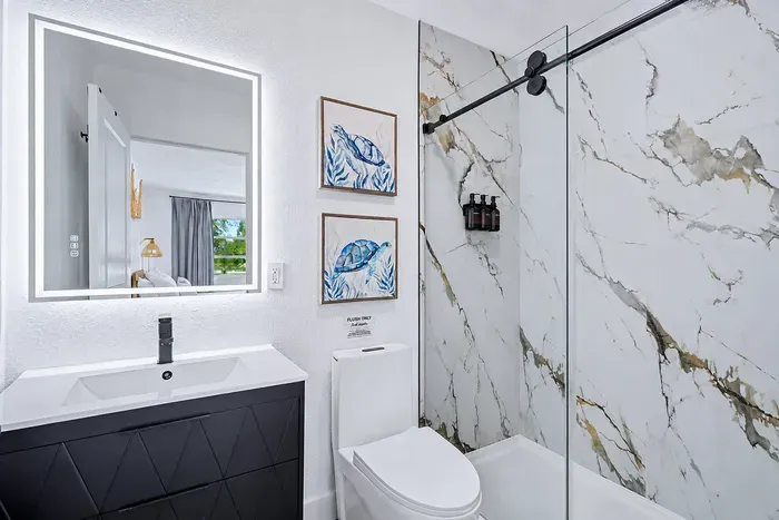 Marble shower walls, glass slider, LED mirror, toiletries ready — the parents' reset button after a full day with the kids.