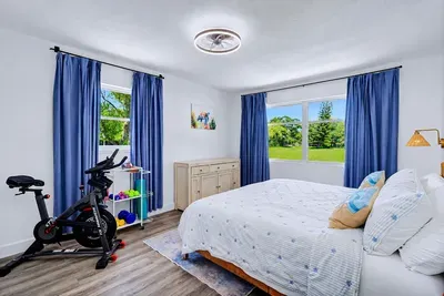 Schwinn IC4, dumbbells, foam roller, and yoga gear — the master doubles as a private home gym, garden views included.