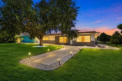 Walk up the lit path at dusk — landscape lights on, tree lit from below, every window glowing — the vacation officially starts here.