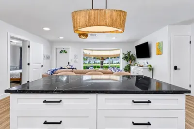 Statement pendant, statement counter — the island is where the group gravitates, glass in hand, waiting on dinner.