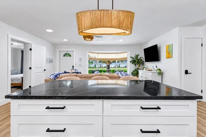 Statement pendant, statement counter — the island is where the group gravitates, glass in hand, waiting on dinner.
