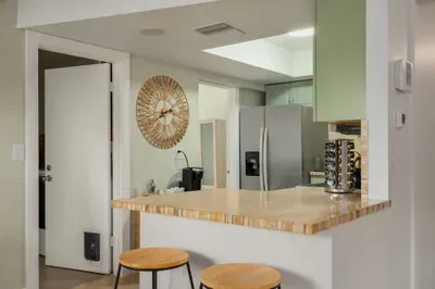Bright, open kitchen bar with natural wood counters, modern appliances, and casual seating. Perfect for quick breakfasts, evening drinks, or chatting while meals are prepared in this inviting, beachy space.
