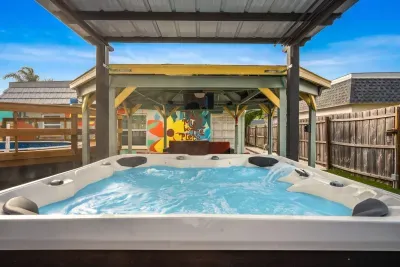 Unwind in your private backyard oasis featuring a bubbling hot tub under a covered pergola. Colorful murals, string lights, and tropical vibes create the perfect spot for sunset soaks, relaxation, and unforgettable evenings.
