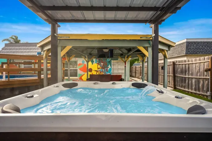Unwind in your private backyard oasis featuring a bubbling hot tub under a covered pergola. Colorful murals, string lights, and tropical vibes create the perfect spot for sunset soaks, relaxation, and unforgettable evenings.