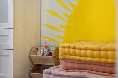 Thoughtful bedroom touches with soft folded linens, cozy textures, and a cheerful sunburst mural. Warm, welcoming details create a playful yet relaxing vibe—perfect for unwinding and feeling right at home.