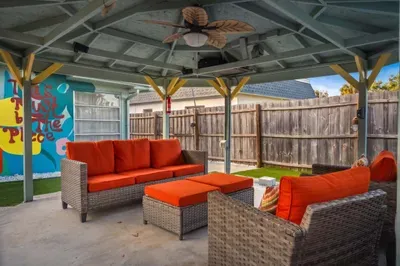 Spacious covered outdoor lounge with plush seating, bold cushions, and a breezy ceiling fan. Perfect for relaxing after a swim, enjoying cocktails with friends, or unwinding in the shade with vibrant, beachy vibes all around.