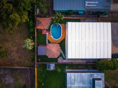 Aerial view of your private backyard oasis featuring a sparkling pool, hot tub, covered lounge, and dining areas. Fully fenced and thoughtfully laid out, this tropical retreat is perfect for relaxing, entertaining, and unforgettable vacation memories