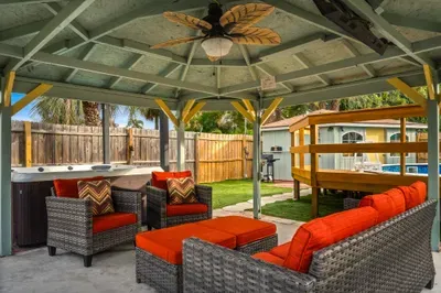 Relax in this covered outdoor lounge featuring plush seating, ceiling fan, and cozy cushions just steps from the hot tub. Perfect for morning coffee, evening cocktails, or gathering with friends in a shaded, tropical setting.