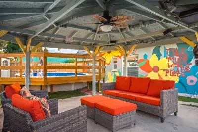 Relax in this vibrant covered lounge with plush seating, ceiling fan, and bold mural backdrop. Perfect for morning coffee or evening cocktails, this cozy outdoor space blends comfort and color for laid-back gatherings and memorable stays.