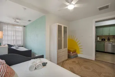 Bright, cheerful bedroom with cozy beds, playful sun mural, and airy coastal style. Soft linens, natural light, and thoughtful details create a welcoming space perfect for families, friends, and relaxed beachside stays.
