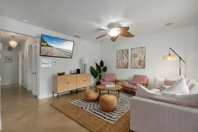 Spacious coastal living room with plush seating, woven accents, and warm natural light. Relax under the ceiling fan, enjoy movie nights, or gather with friends in this stylish, open space made for comfort and connection.