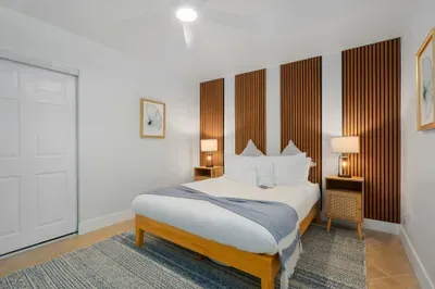 Calm and modern bedroom with plush bedding, warm wood panel accents, and soft ambient lighting. Designed for comfort and tranquility, this inviting space is perfect for restful nights and slow, relaxing mornings.
