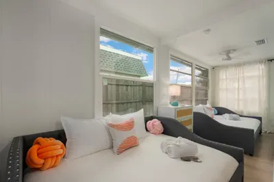 Bright, airy bedroom with plush beds, coastal décor, and abundant natural light. Relax in comfort with soft linens, playful accents, and a serene layout—perfect for restful nights and easygoing mornings by the beach.