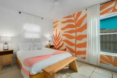 Bright, stylish bedroom retreat with plush bedding, tropical mural accents, and serene backyard views. Natural light, cozy textures, and a calming color palette create the perfect space to unwind after a day of sun and fun.