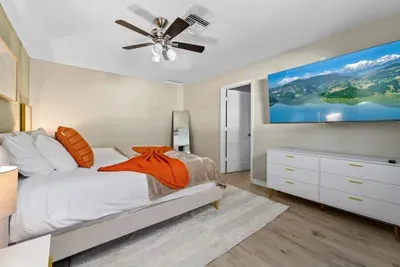 Main bedroom with a king bed, ceiling fan, TV, and ensuite bathroom.