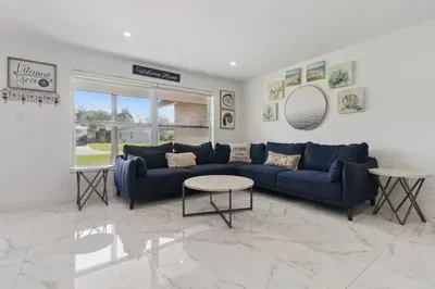 Unwind in this bright and comfortable living space, featuring a plush, family-sized sofa perfect for movie nights, afternoon naps. Natural light pours in through large windows, creating a warm and welcoming atmosphere.