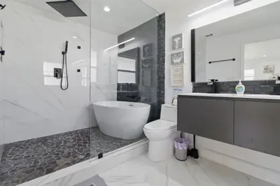This spacious bathroom, featuring a luxurious bathtub perfect for soaking after a long day. The wide sink offers plenty of counter space, while the large mirror adds a touch of elegance and makes the space feel even more open and bright.