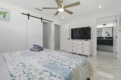 Relax in this comfortable bedroom featuring a queen-sized bed, perfect for a restful night’s sleep. Enjoy your favorite shows on the flat-screen TV, and conveniently access your private bathroom just steps away.