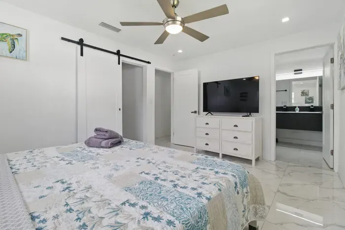 Relax in this comfortable bedroom featuring a queen-sized bed, perfect for a restful night’s sleep. Enjoy your favorite shows on the flat-screen TV, and conveniently access your private bathroom just steps away.