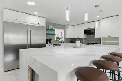 This sleek, modern kitchen features a spacious counter with four high chairs—ideal for casual dining, morning coffee, or simply keeping the cook company.