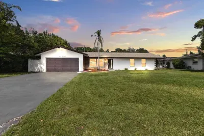 This peaceful evening view captures the side of the house, with the driveway and garage softly illuminated in the warm glow of twilight.