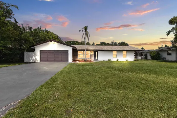 This peaceful evening view captures the side of the house, with the driveway and garage softly illuminated in the warm glow of twilight.