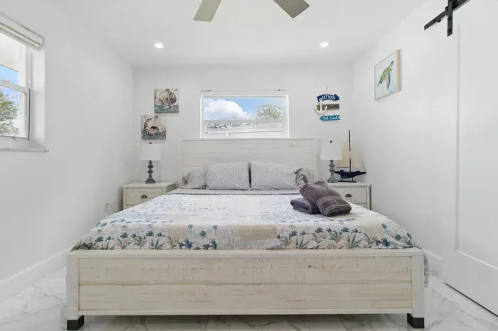 Enjoy a restful stay in this inviting bedroom featuring a plush queen-sized bed, framed by two windows that fill the space with natural light. Two small side tables add both charm and functionality. A comfortable and relaxing space to unwind.