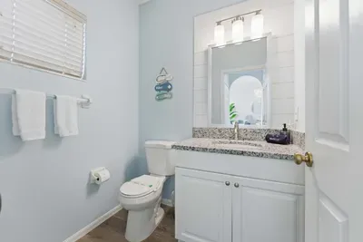 Fresh and airy bathroom with coastal blue walls, granite vanity, and crisp white accents. Thoughtfully designed for comfort and style, it’s the perfect space to refresh after a day of sun and sea.