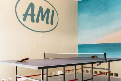 Enjoy endless entertainment in your private game space. Featuring a full-size ping pong table set beneath bold AMI wall art and a vibrant beach mural backdrop.