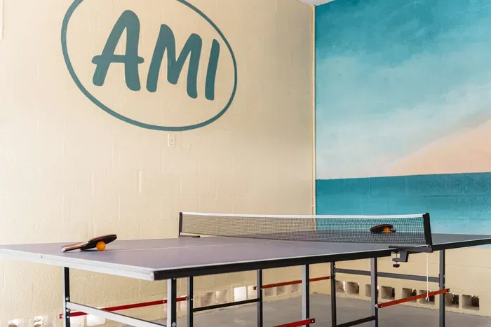 Enjoy endless entertainment in your private game space. Featuring a full-size ping pong table set beneath bold AMI wall art and a vibrant beach mural backdrop.