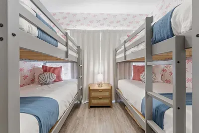 Charming coastal bunk room with two twin-over-twin beds, beachy décor, and bright natural light. Perfect for kids or friends, this fun and cozy space brings playful seaside vibes to your stay.