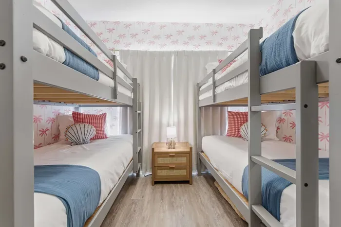 Charming coastal bunk room with two twin-over-twin beds, beachy décor, and bright natural light. Perfect for kids or friends, this fun and cozy space brings playful seaside vibes to your stay.