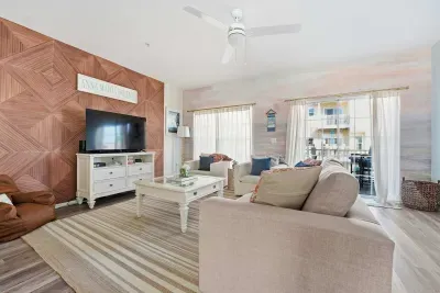 Featuring a striking wood accent wall, large flat-screen TV, plush seating, and soft natural light throughout. Open and airy with seamless flow to the kitchen—perfect for relaxing nights or gathering with family and friends.