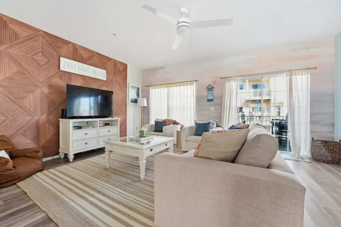 Featuring a striking wood accent wall, large flat-screen TV, plush seating, and soft natural light throughout. Open and airy with seamless flow to the kitchen—perfect for relaxing nights or gathering with family and friends.