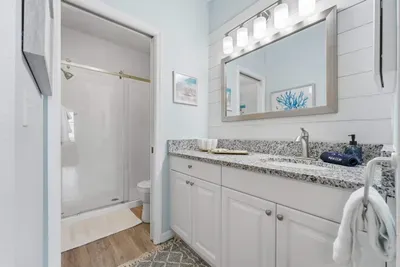 Elegant ensuite with granite countertops, dual sinks, and a spacious walk-in shower. Soft coastal hues and chic details create a relaxing spa-like retreat connected to the master bedroom for ultimate comfort and private