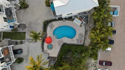 Aerial view of the tropical pool area featuring a sparkling pool, relaxing hot tub, and sun loungers. Surrounded by palm trees, it’s the perfect spot to unwind and soak up the Florida sunshine.