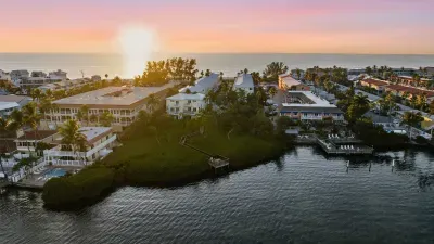 Serene coastal scenery at sunset with calm waters, lush greenery, and beachside homes glowing in golden light. The perfect blend of tranquility and tropical beauty for your seaside getaway.