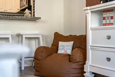 Cozy reading nook with a plush leather bean bag and coastal-themed pillow. Tucked beside the kitchen, it’s the perfect spot to unwind with a book, sip morning coffee, or simply relax in seaside comfort and charm.