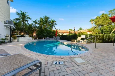 Sparkling community pool surrounded by lush palms and sunny lounge chairs. Perfect for a refreshing swim or relaxing under the warm coastal sky.