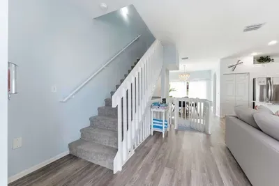 Bright and airy entryway with coastal hues, modern flooring, and an open staircase leading to the main living space. A welcoming start to your relaxing beachside getaway.