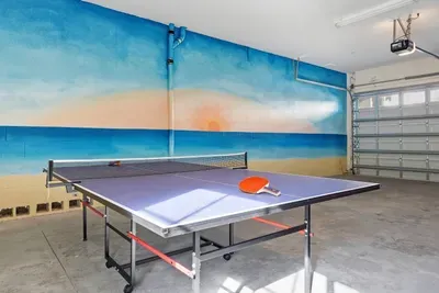 Spacious game area with a full-size ping pong table set against a vibrant beach mural. Perfect for friendly tournaments and family fun, this bright, open space offers plenty of room to play, laugh, and create unforgettable vacation memories.