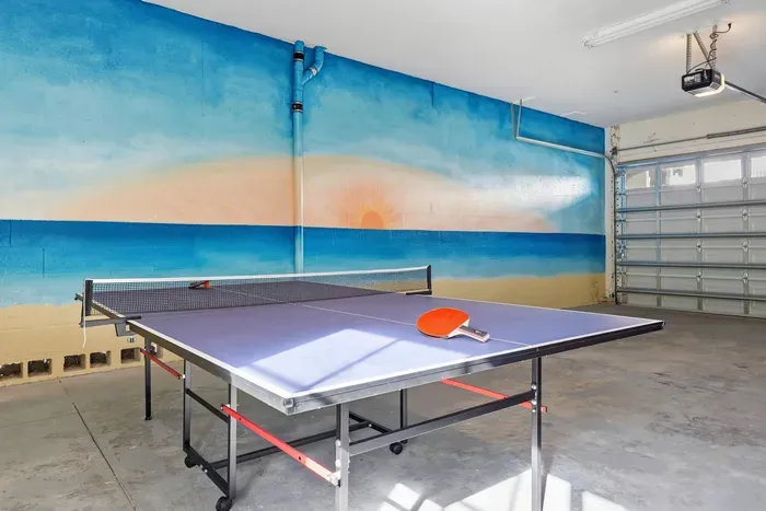 Spacious game area with a full-size ping pong table set against a vibrant beach mural. Perfect for friendly tournaments and family fun, this bright, open space offers plenty of room to play, laugh, and create unforgettable vacation memories.