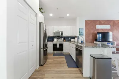 Modern open kitchen with stainless-steel appliances, granite countertops, and a stylish blue backsplash. The bright, airy layout flows into the living area, making it ideal for cooking, entertaining, and enjoying coastal comfort.