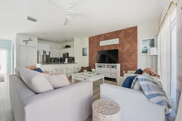 Spacious open-concept living area with coastal charm and designer touches. Relax on plush seating and enjoy the stunning wood accent wall and large TV.