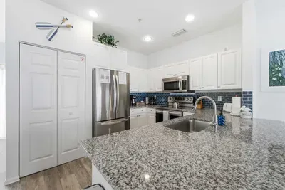 Sleek coastal kitchen with granite counters, stainless-steel appliances, and a chic blue tile backsplash. Spacious and bright, it’s perfect for cooking, entertaining, and enjoying a relaxed seaside vibe with modern flair.