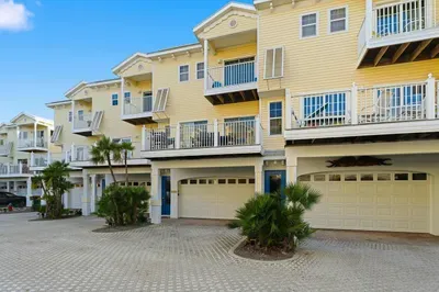 Charming coastal townhomes with sunny yellow exteriors, private balconies, and tropical landscaping. A welcoming seaside community just steps from the beach and ocean breezes.